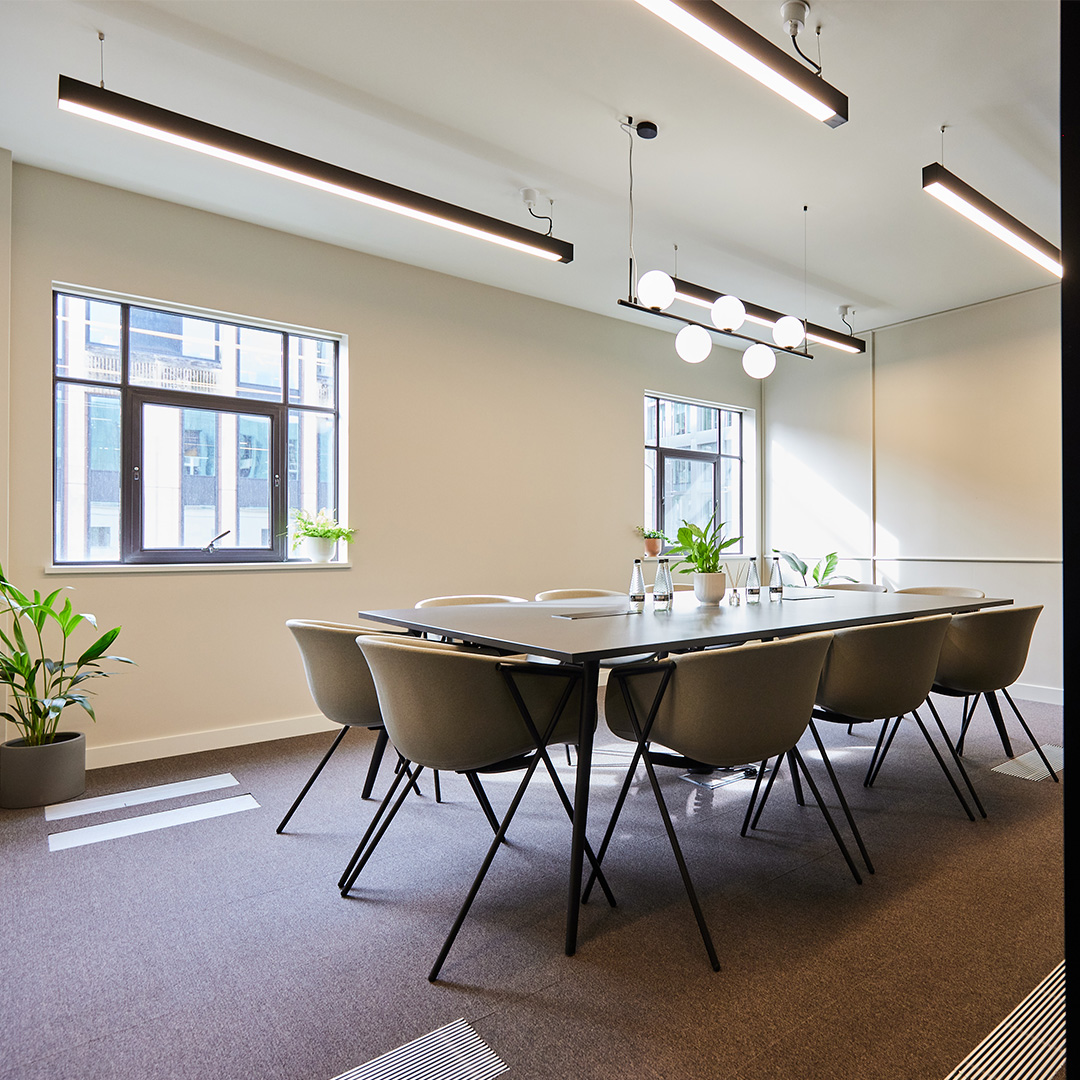 Elegant meeting room in a London office interior design, with comfortable chairs, a large table, and plants