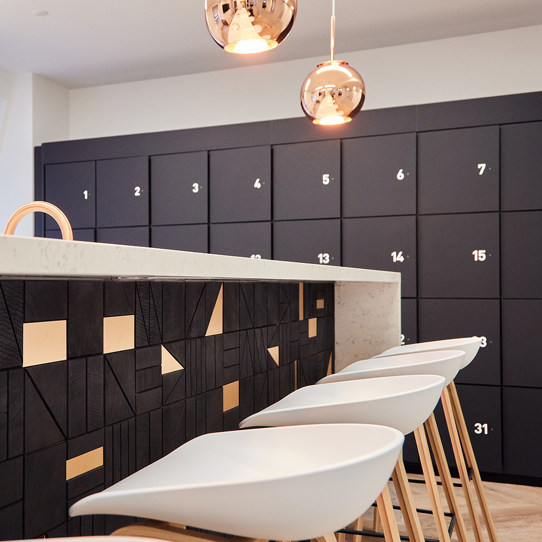 A functional and stylish office teapoint with custom black joinery and shiny copper pendant lighting in a functional and stylish workspace