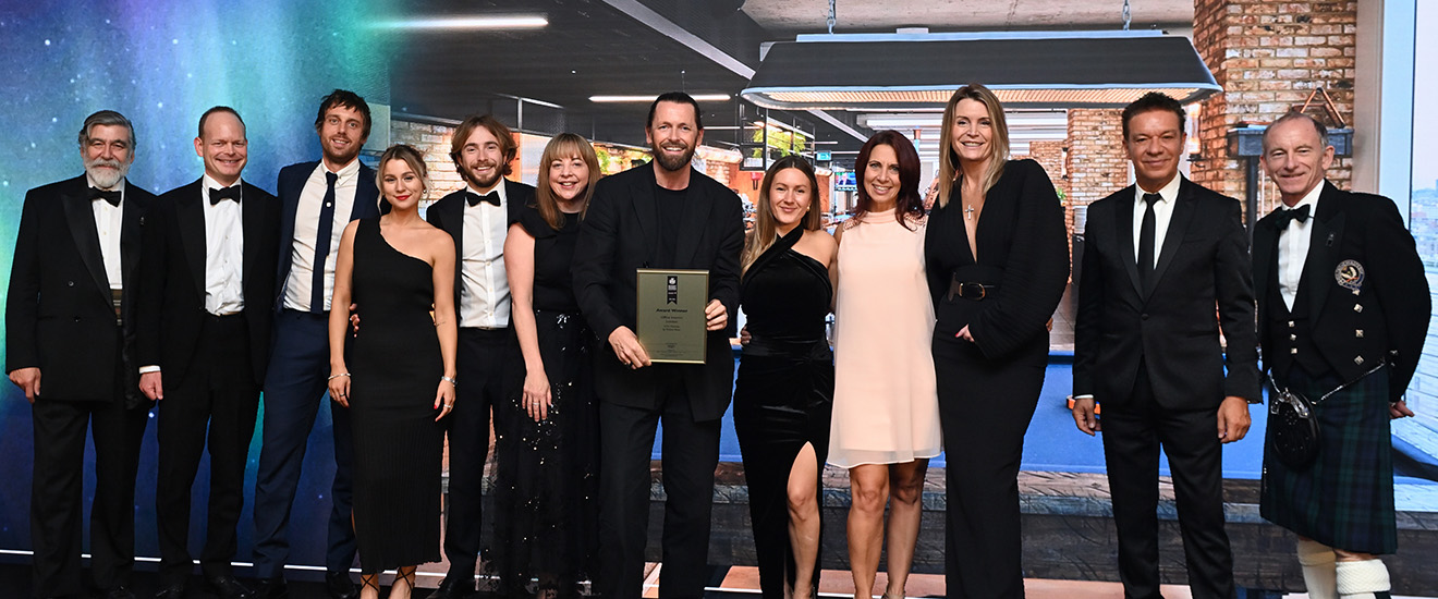 Group of people in formal attire holding an award, with a cosmic background.