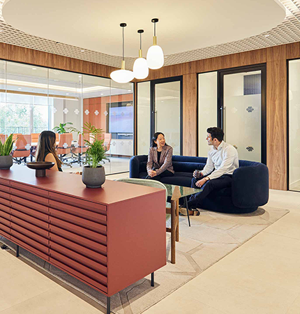 Modern office lobby with two people seated and having a conversation, with stylish furniture and interior design.