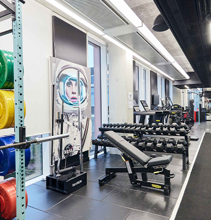 Modern gym interior with equipment and weight rack at XTX Markets workspace.