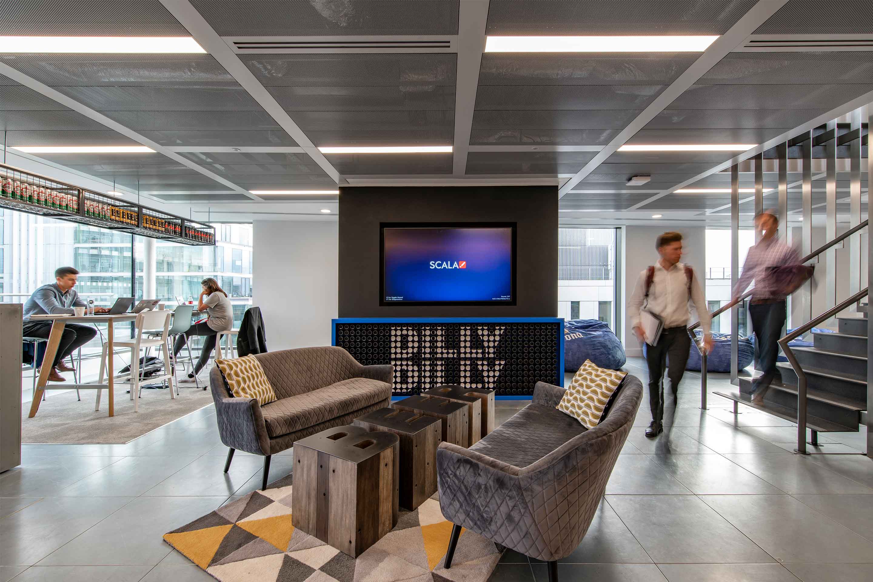 Modern Budweiser office lounge with stylish furniture and people working and walking.