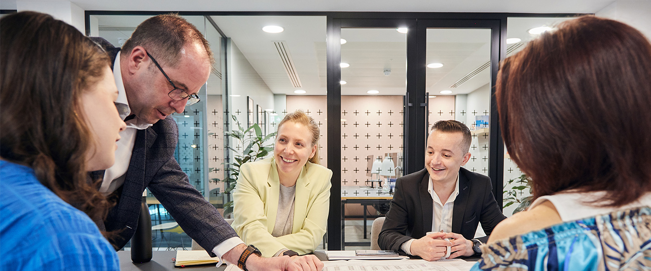 Colleagues collaborating in a relaxed setting, smiling and examining documents together smiling