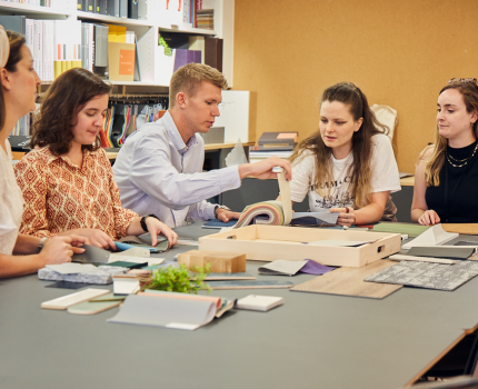 A group of individuals engaged in a collaborative work session at a table with papers and materials.