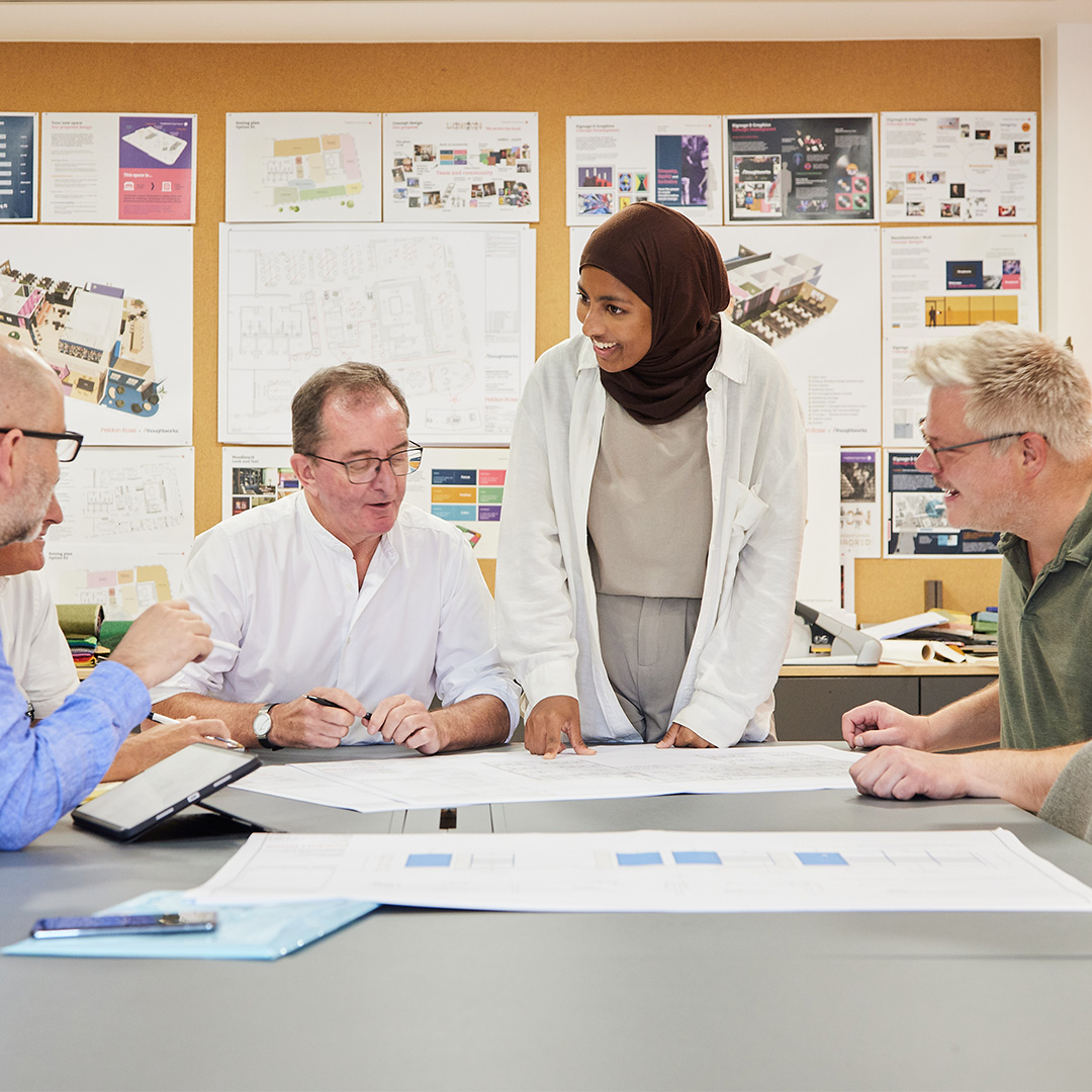 A group of interior designers seated at a table, engaged in dialogue and interaction, highlighting teamwork and community