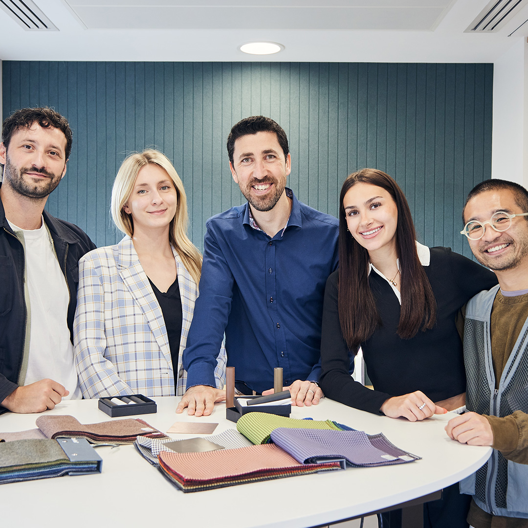 Several people in a team gathered closely, all smiling and posing for a group photo, showcasing camaraderie and happiness