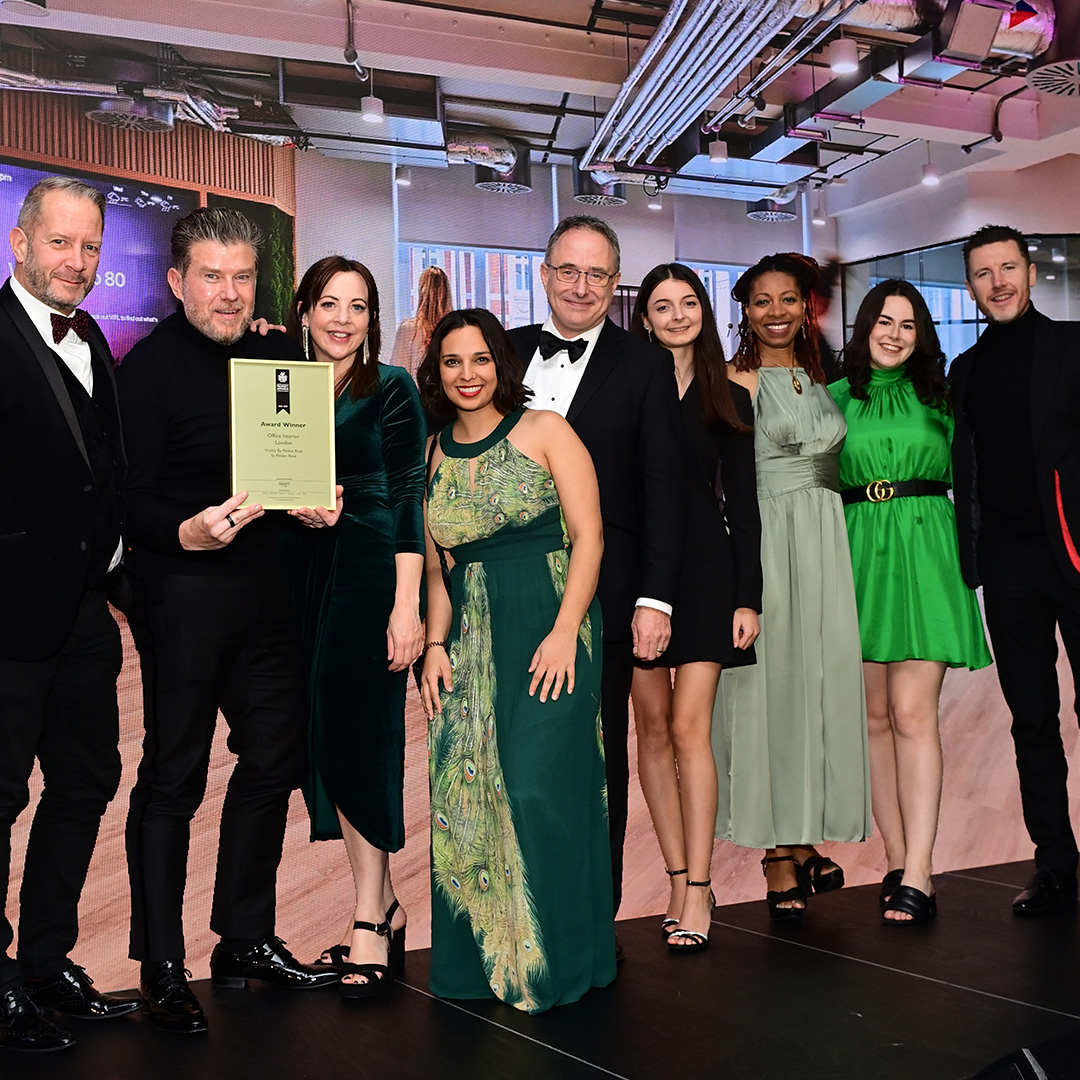 A group of individuals in formal attire proudly holding an award, celebrating their achievement together