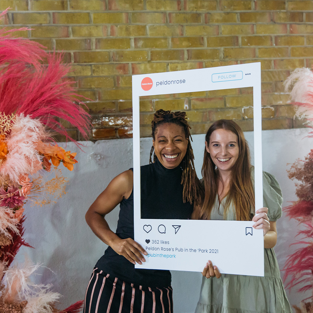 Two women hold a photo frame up showcasing their bond and happiness in a shared experience