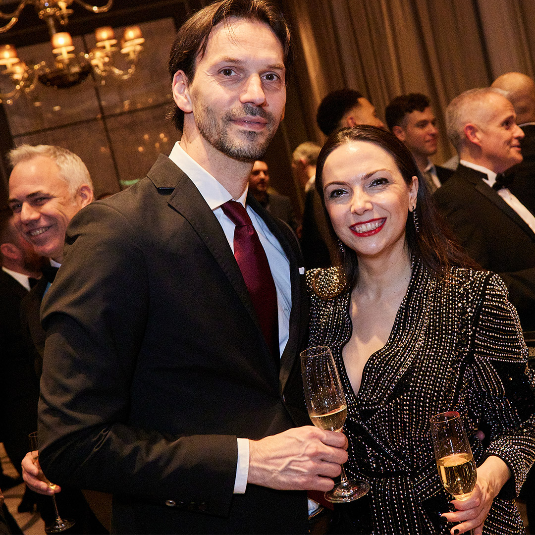 A man and woman clink wine glasses together, enjoying a celebratory moment at a work christmas party event