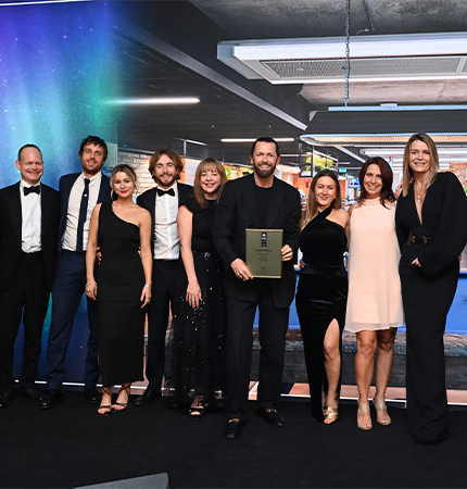 Group of people in formal attire holding an award, with a cosmic background.