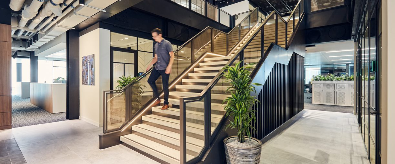 Mondrian Modern office interior with an elegant staircase and plants.