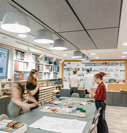 Interior of a busy design studio with people working and materials on tables.