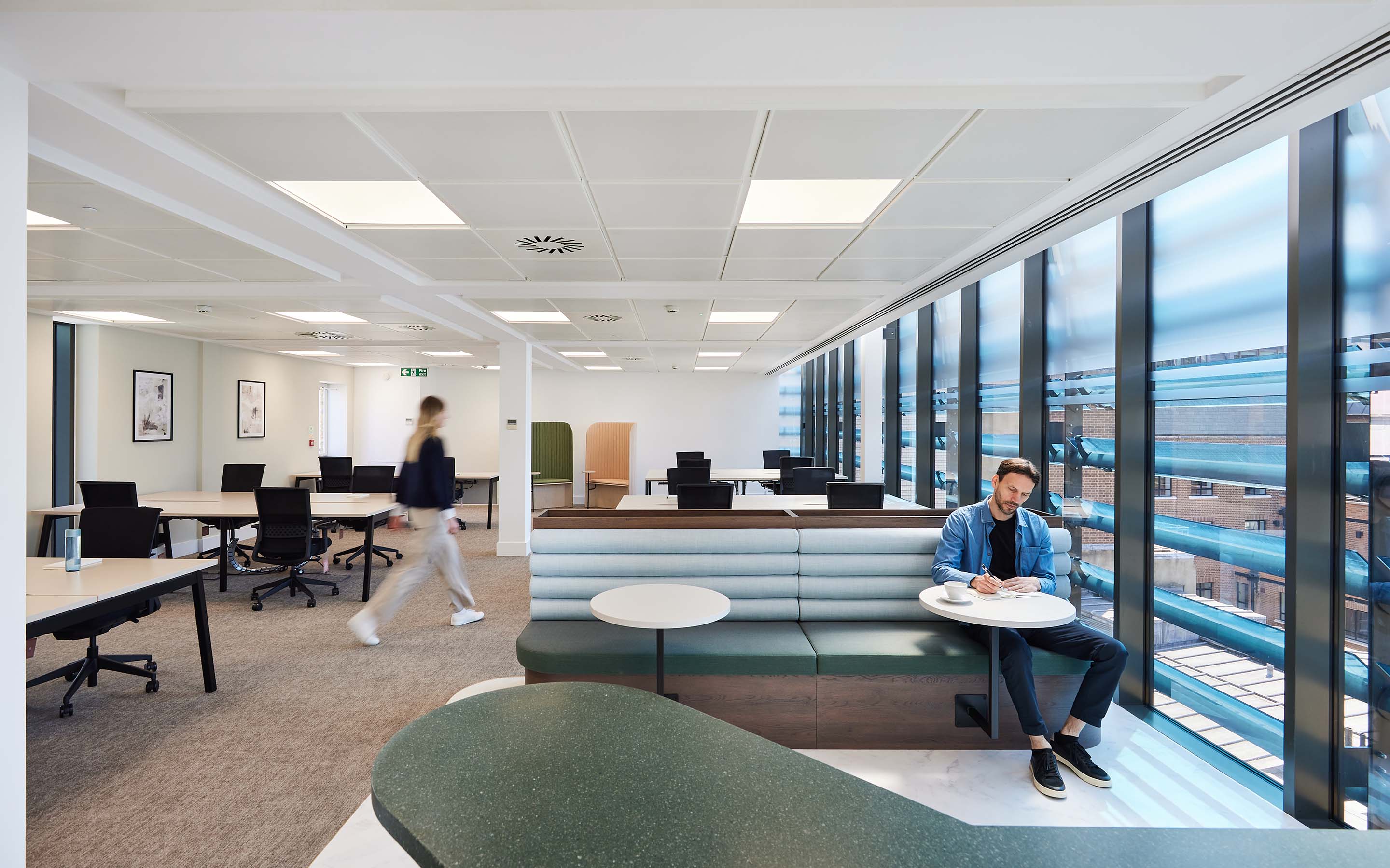 Modern office interior with desks, seating area, and large windows.