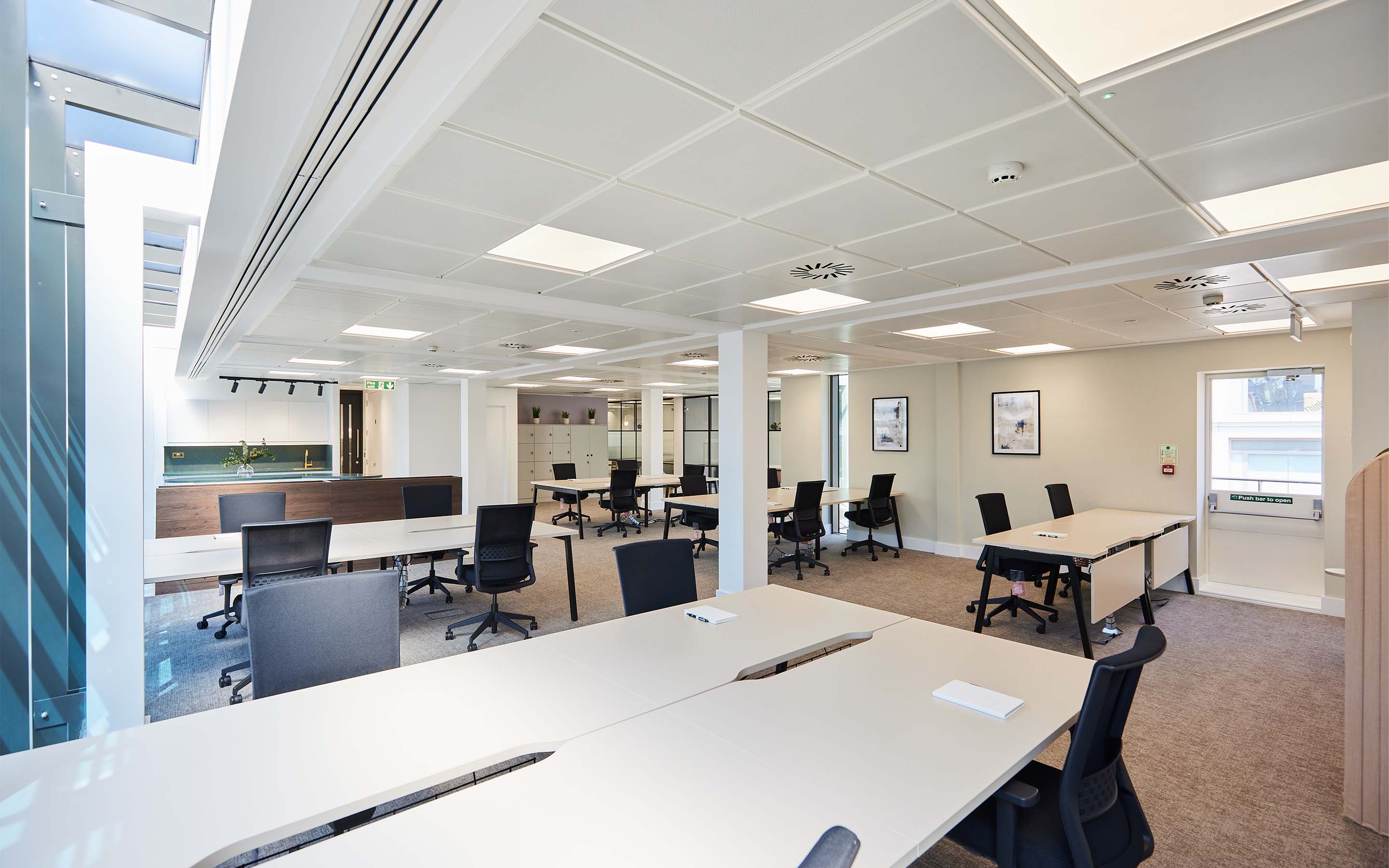 Modern office interior with desks, chairs, and bright lighting.