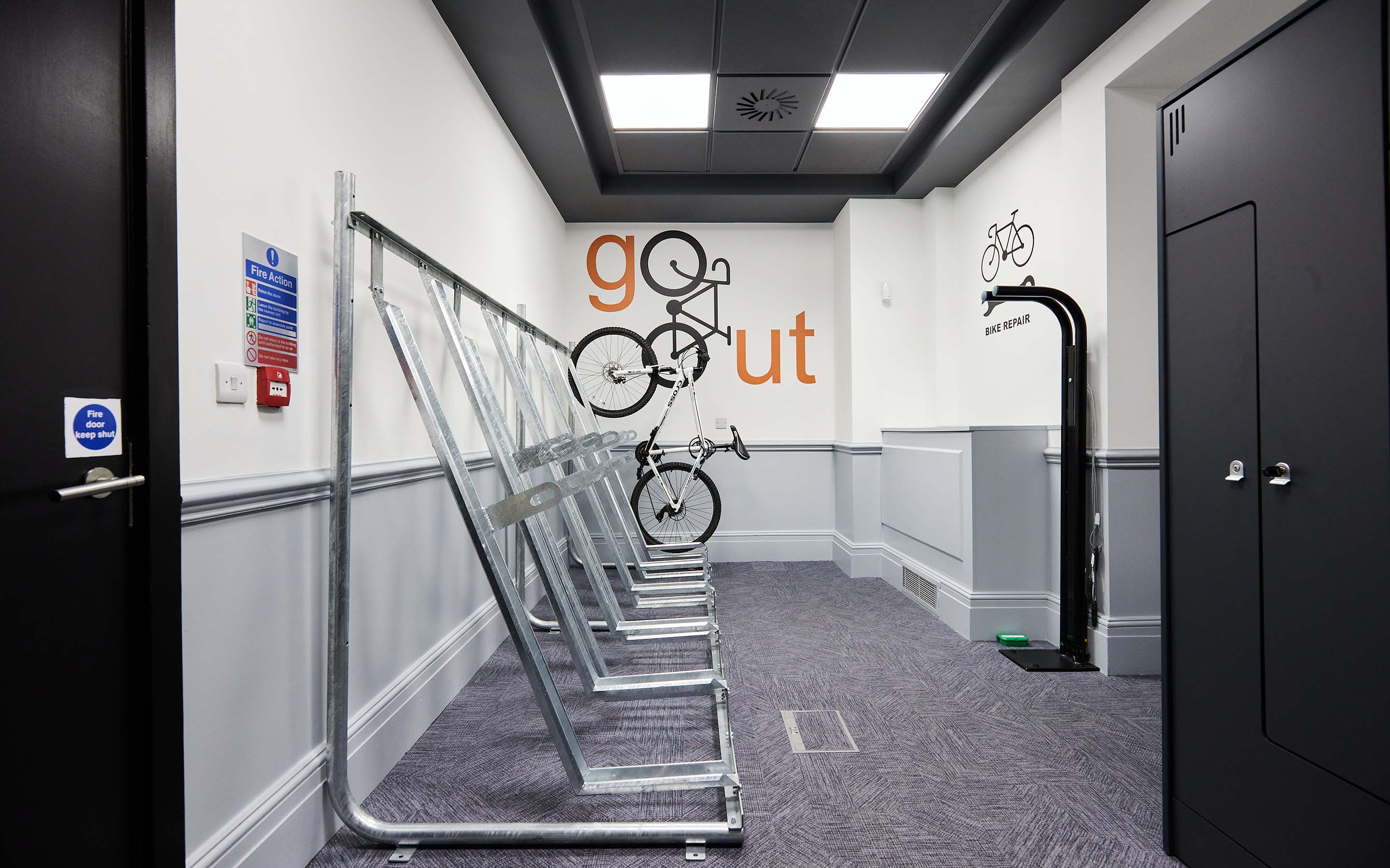 Indoor bike parking rack with a single bicycle, signs for bike repair, and a 