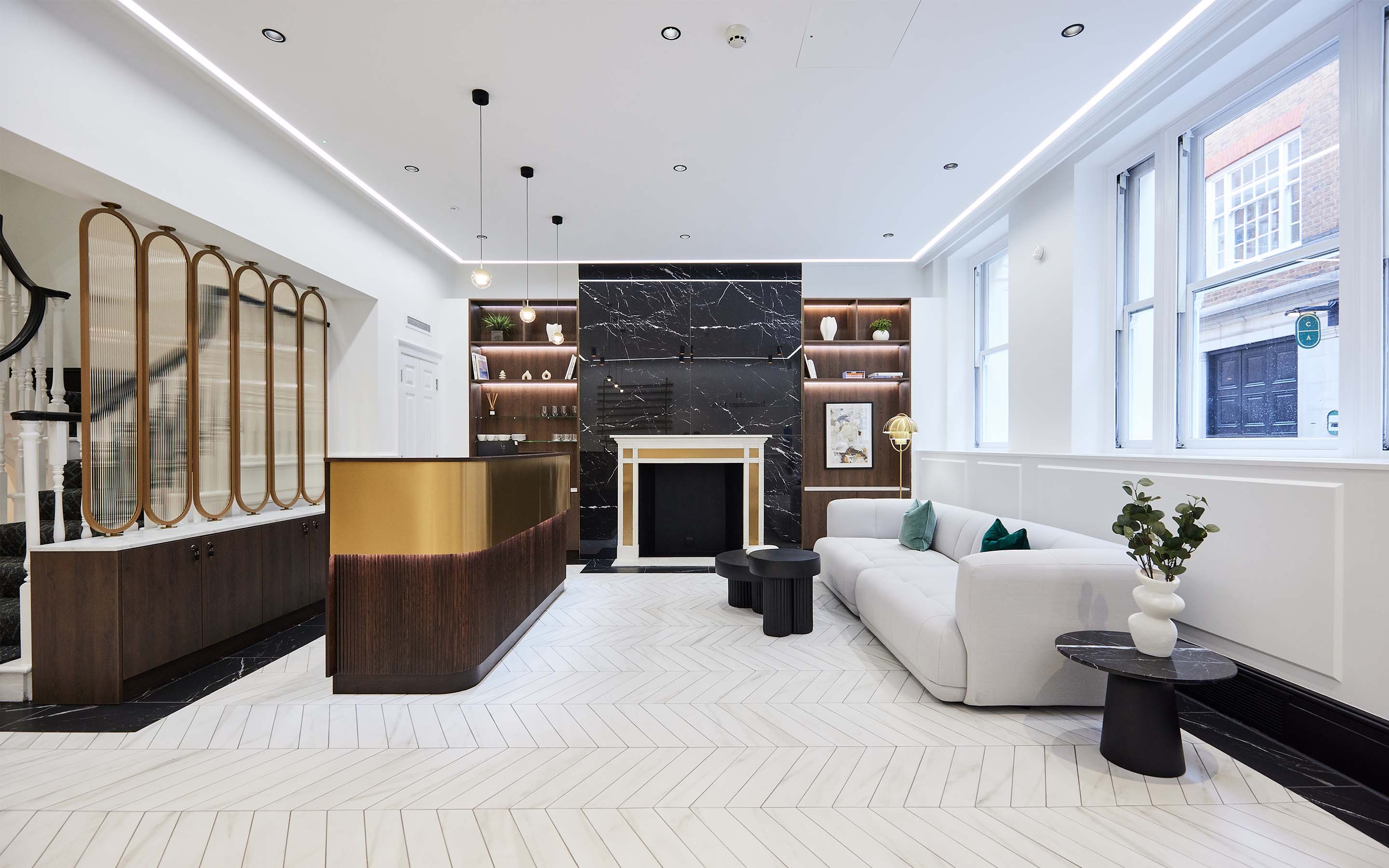 Modern lobby with white herringbone floor, black marble fireplace, and plush seating.