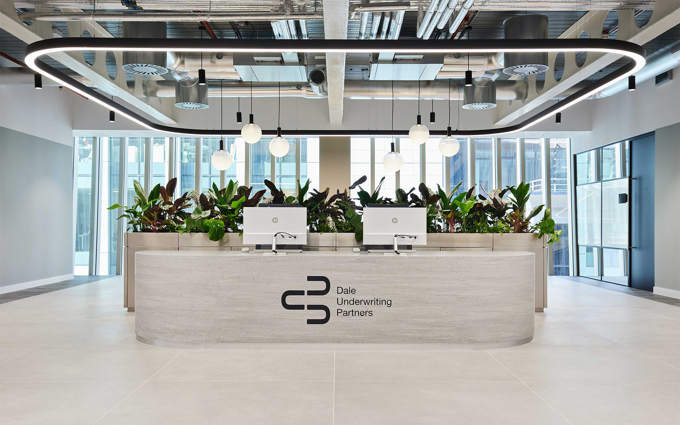 Modern office reception area with plant decor and circular lighting fixtures.