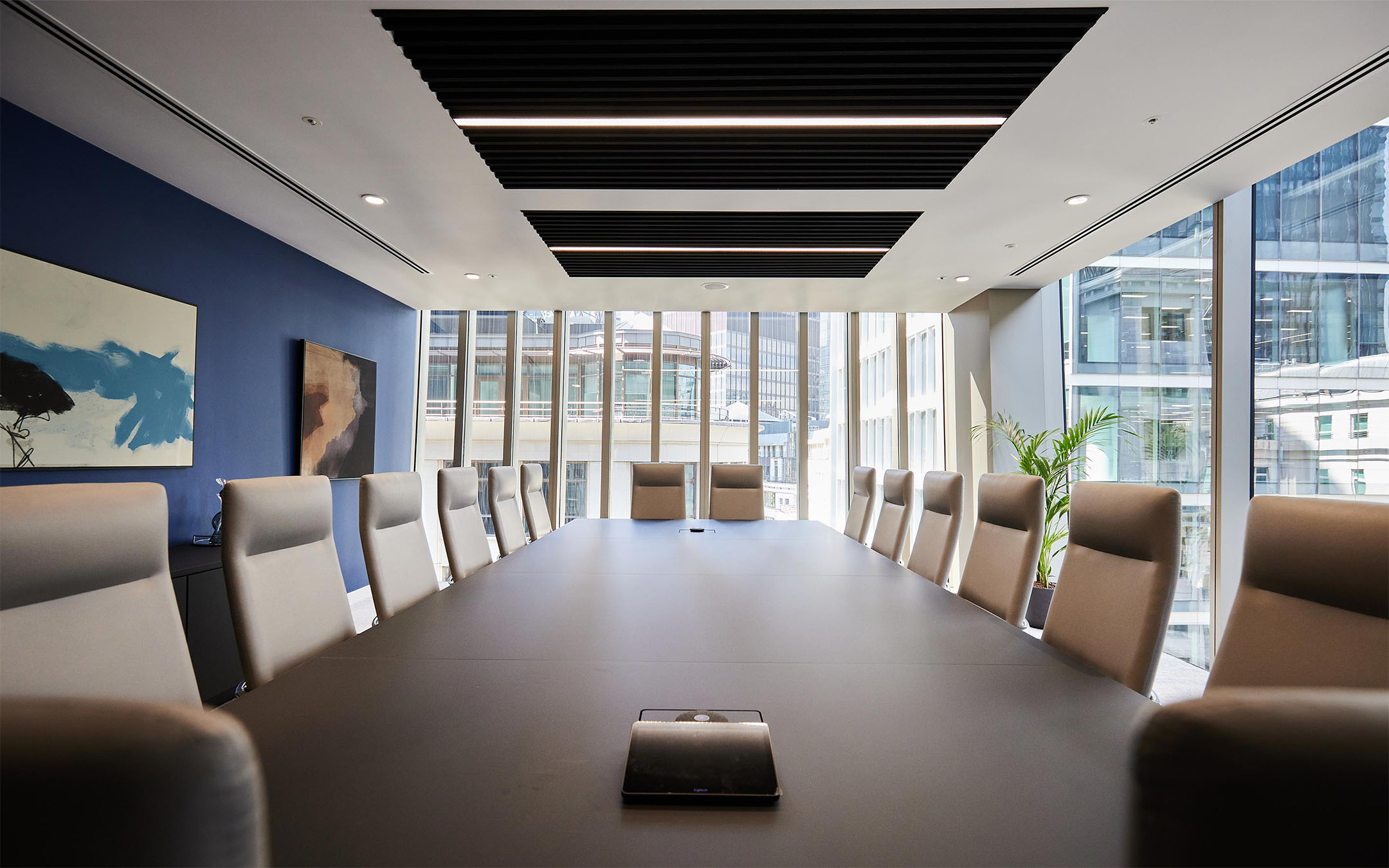 Modern conference room with a long table, chairs, and large windows with city view.