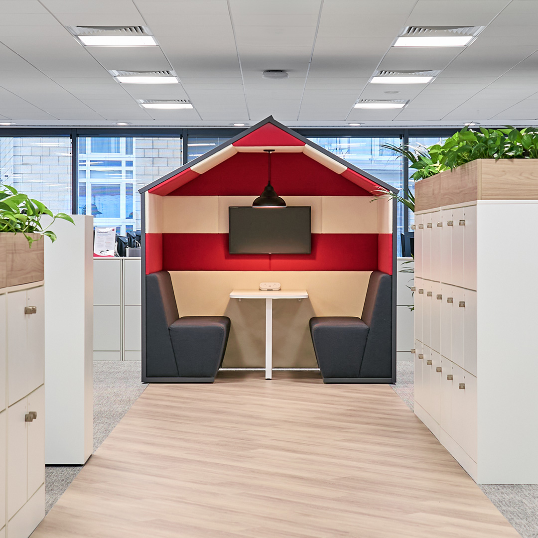 A collaboration booth in a modern office, in the style of a beach hut with red and white stripes