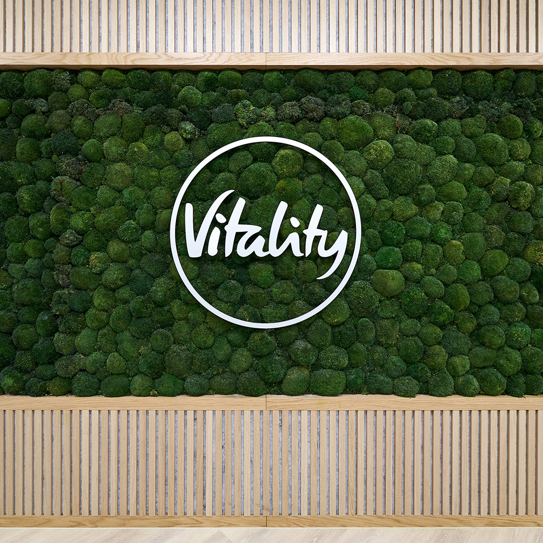 A wall of plants with bespoke wooden joinery and a company logo in a modern office