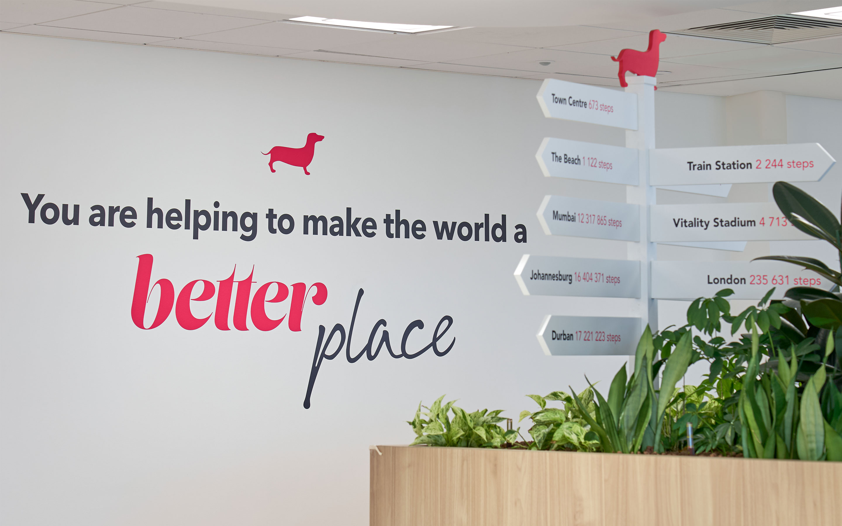 Company values and printed on a white wall, with pink iconography and plants