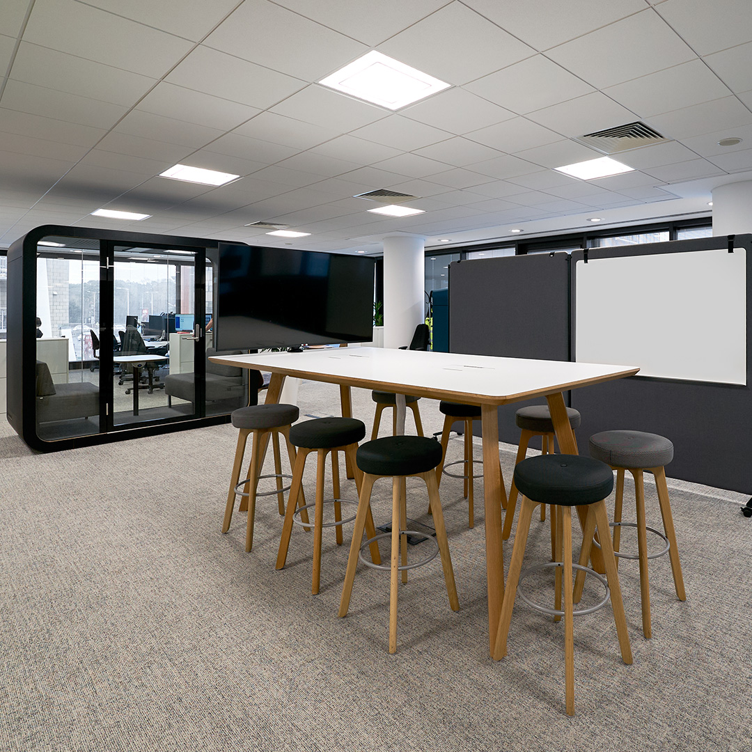 A high collaboration table with sleek stools in a modern, sophisticated office