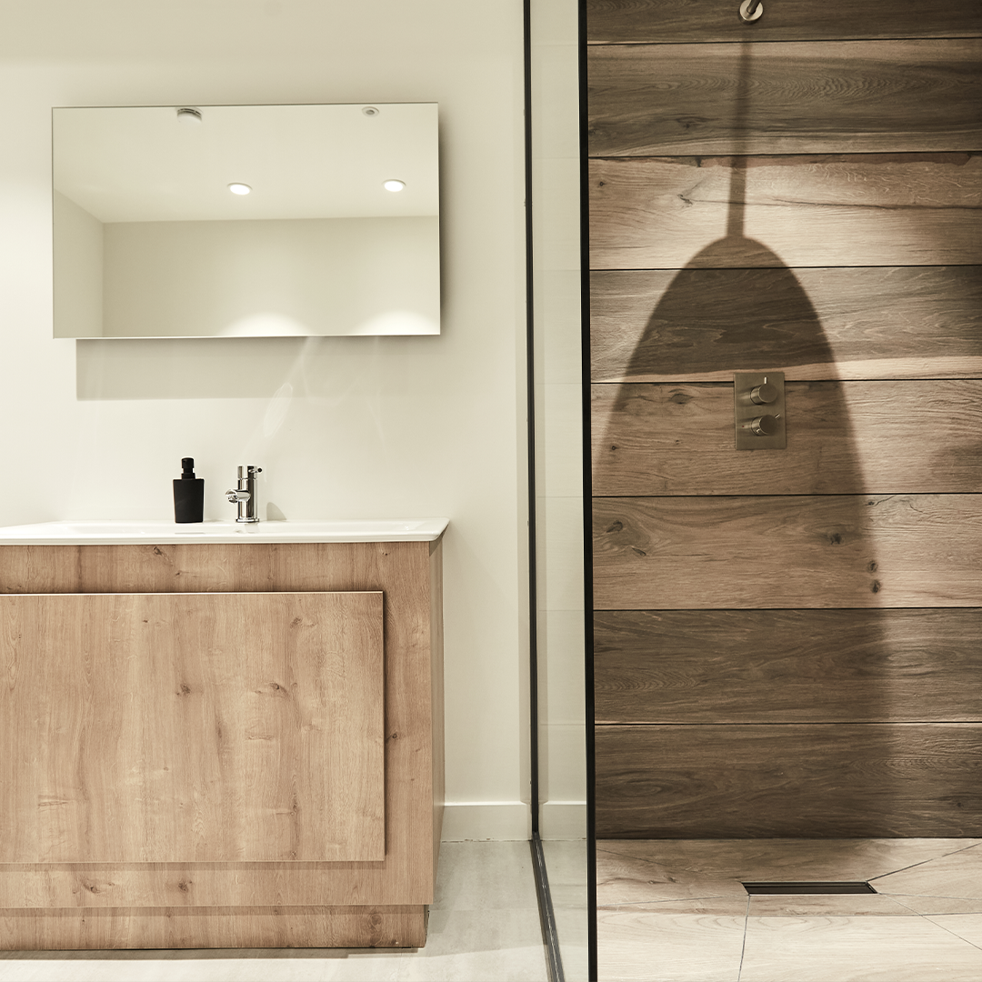 A modern shower with wooden panels next to a wooden sink.