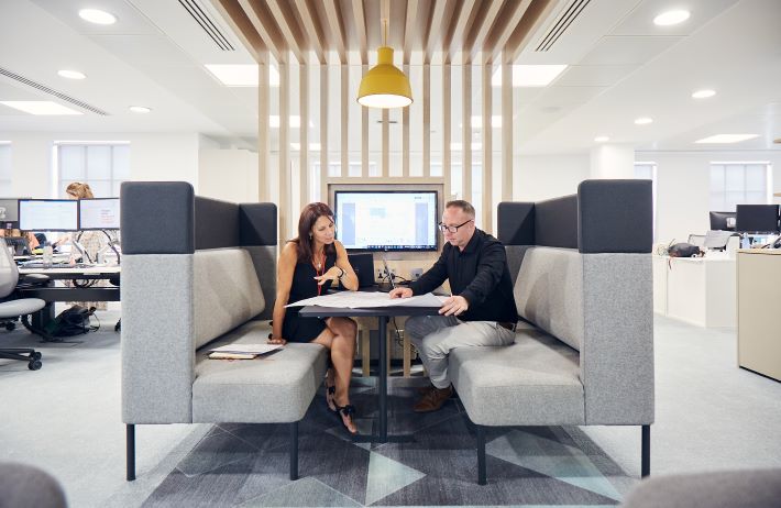 Two professionals working at a table in a modern office space.