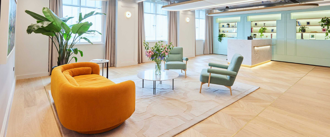 Modern office lobby with plants, a yellow sofa, and minimalist reception desk.