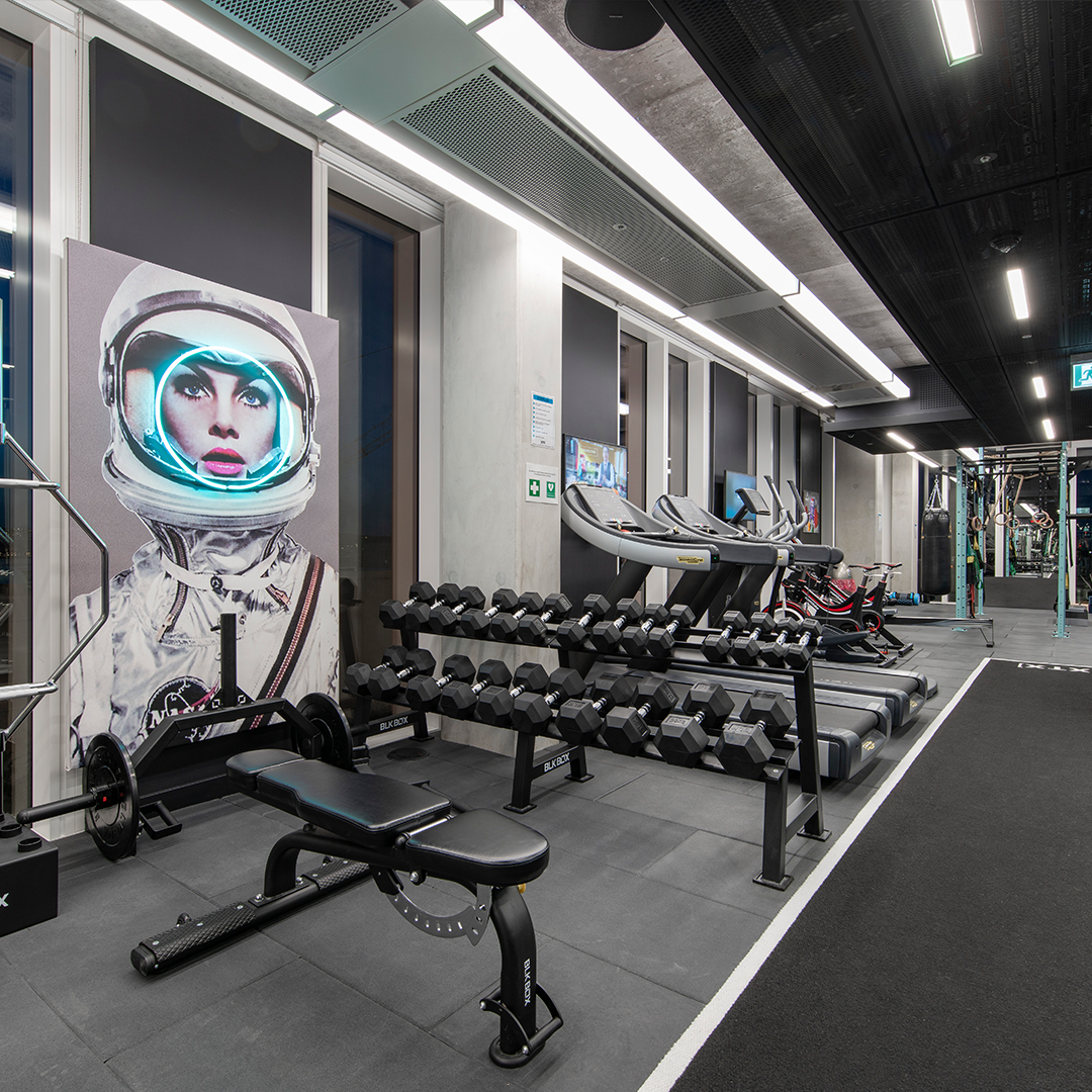 XTX gym space with a bench and free weights next to some running machines.