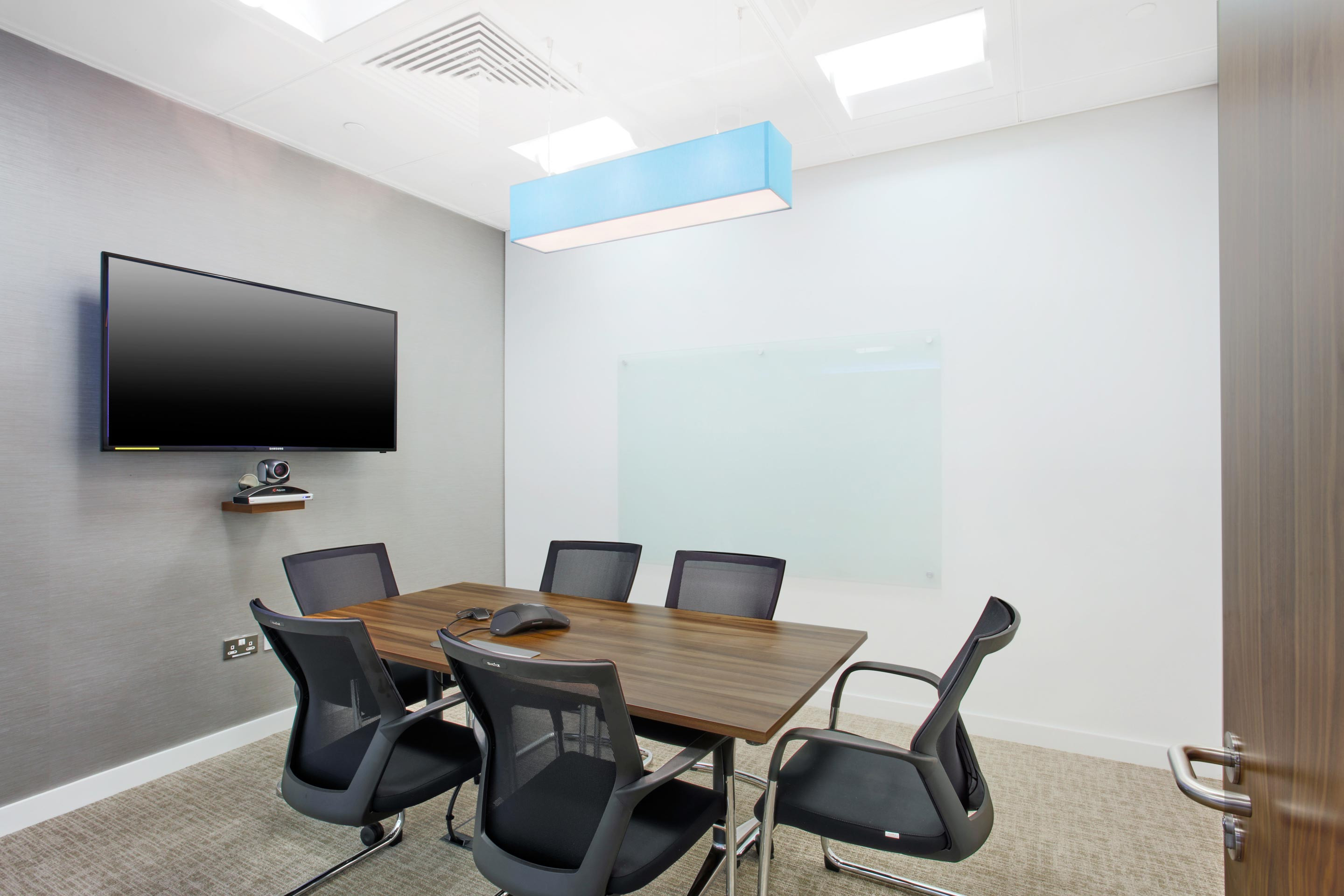 Meeting space equipped with a TV and dark wooden table and chairs